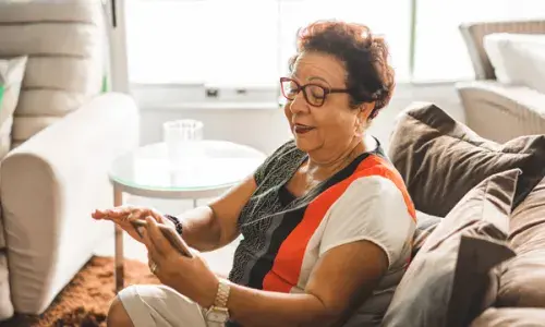 Lady on sofa looking at a mobile phone - National Grid's Grid for Good conference calls for elderly in Syracuse