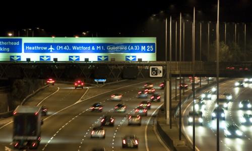 Cars driving along the M25 motorway in England at night