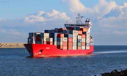 A red ship loaded with containers coming in to the Port of Tyne