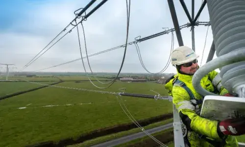 Man wearing PPE at height working on stringing new T-pylon overhead lines