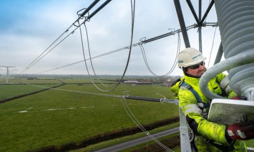 Man wearing PPE at height working on stringing new T-pylon overhead lines