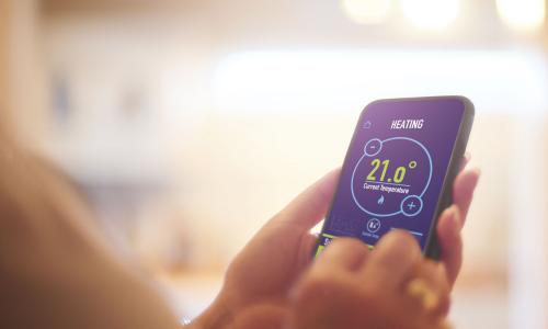 Hands holding a smart device showing heating and current temperature information - used for the National Grid story 'The future of home heating in a net zero UK'