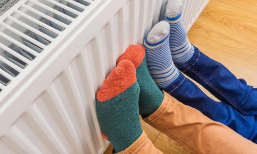 Two pairs of feet in colourful socks held against a radiator