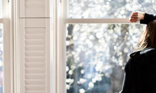 Woman looking through a window - social distancing - used for the National Grid story 'Caring for mental health during a crisis'