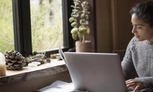 Woman working on a laptop in front of a window - used for the National Grid story 'Looking after our people in uncertain times'