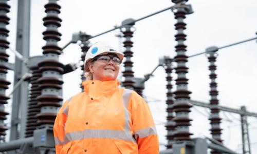 National Grid woman engineer wearing hard hat and orange high-vis jacket at Burwell substation
