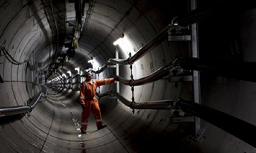 Engineer wearing orange overalls and a hard hat standing inside National Grid's London Power Tunnel
