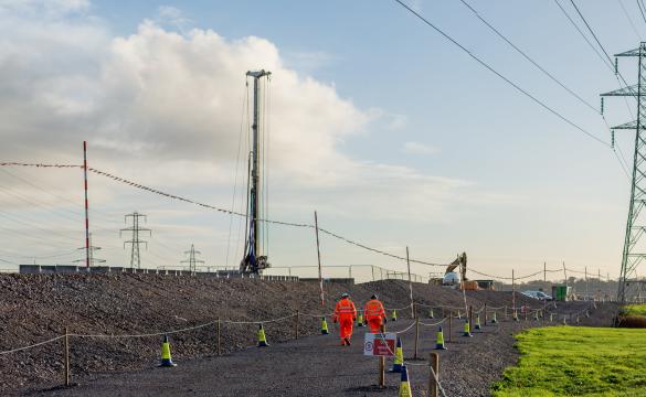 Two people walking down stone path near pylons