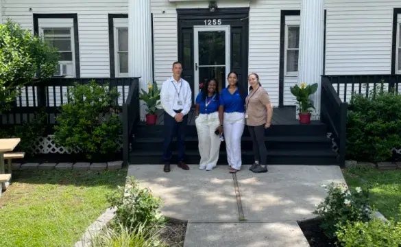 4 people Standing ahead of a Building