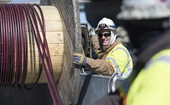 Crew members handling power line Cable