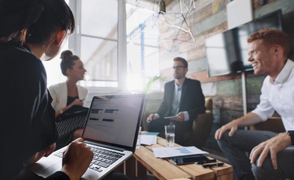 Businesswoman working on laptop whilst in meeting