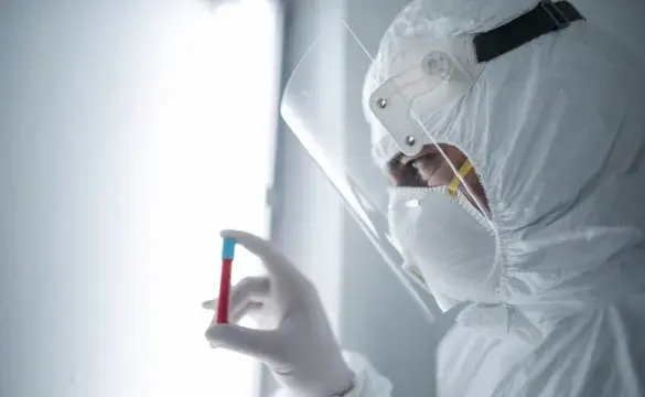 Person wearing full PPE holding blood vial used for National Grid 'Backing the quest for a COVID-19 vaccine' story