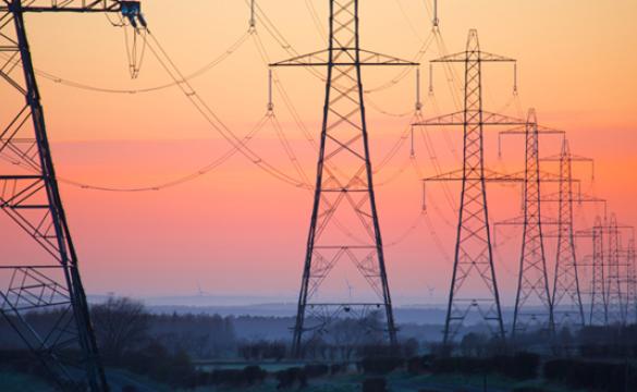 Row of lattice electricity pylons against an orange sky