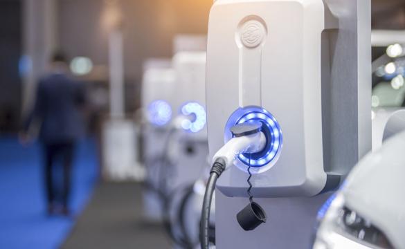 Electric vehicle charging point in garage with man walking away in background - used for the National Grid article 'Smart ways to shift the journey towards EVs for everyone into the fast lane'