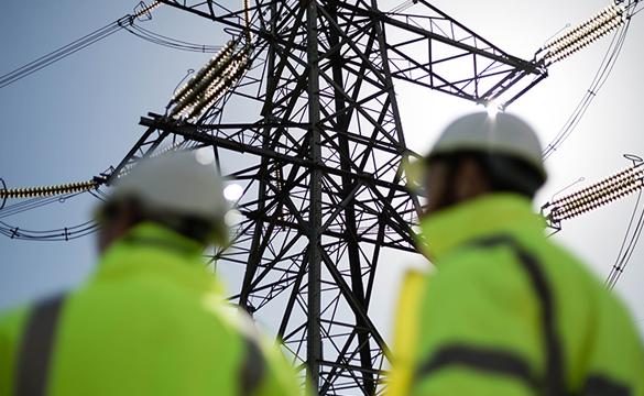 National Grid innovation - two engineers wearing PPE inspecting lattice electricity transmission pylon