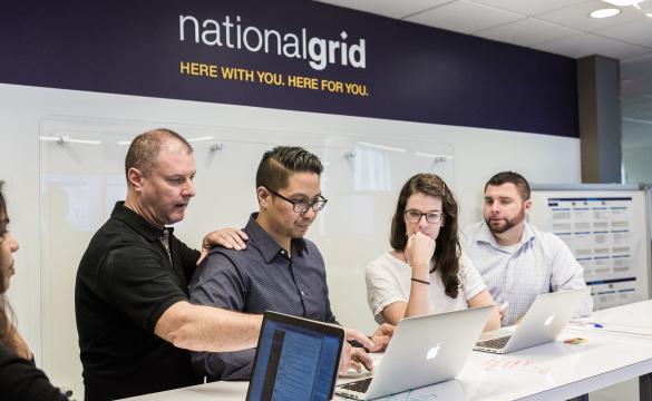 Five National Grid representatives working at a high desk with a white board in the background