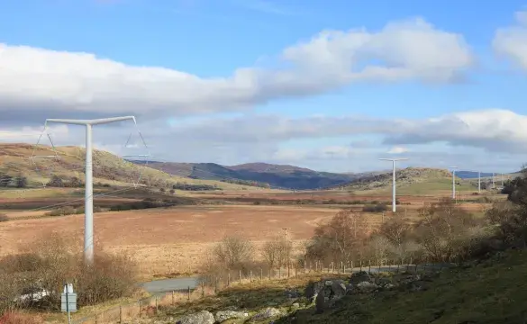 An overview of Lake Bala under a cloudy blue sky with electricity masts extending into the background 