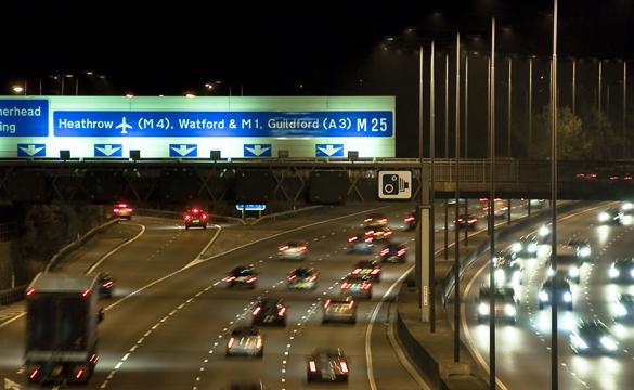 Cars driving along the M25 motorway in England at night