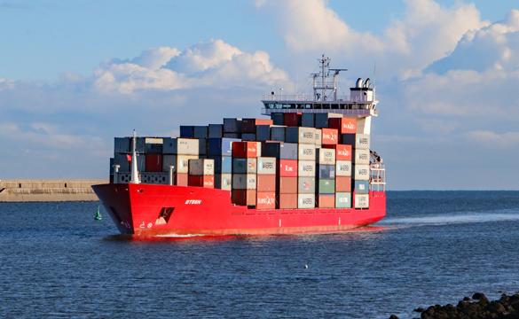 A red ship loaded with containers coming in to the Port of Tyne