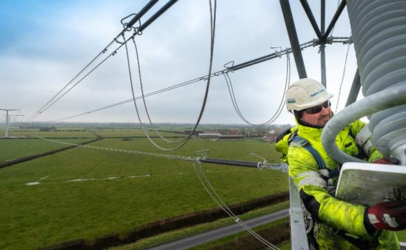 Man wearing PPE at height working on stringing new T-pylon overhead lines