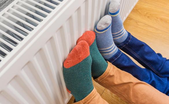 Two pairs of feet in colourful socks held against a radiator