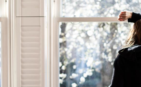 Woman looking through a window - social distancing - used for the National Grid story 'Caring for mental health during a crisis'