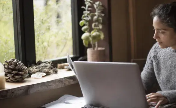 Woman working on a laptop in front of a window - used for the National Grid story 'Looking after our people in uncertain times'