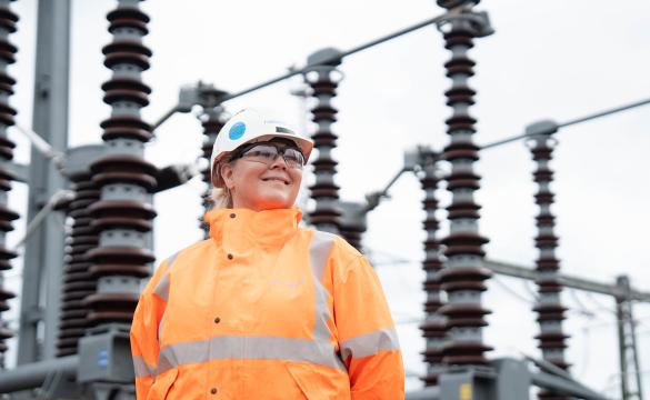 National Grid woman engineer wearing hard hat and orange high-vis jacket at Burwell substation