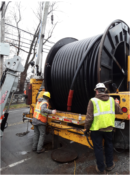 Workers installing large underground cable reel