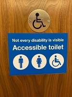 Disability toilet sign on wooden door for National Grid article on disability