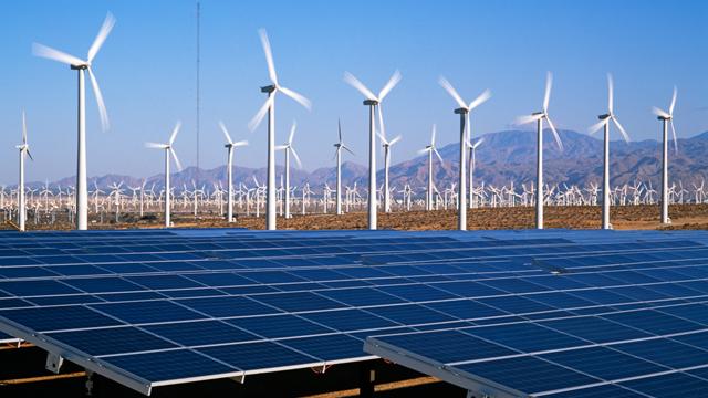 Solar panels and onshore wind farm with mountains in the background