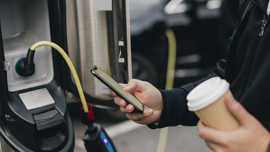 Person charging EV and holding coffee cup