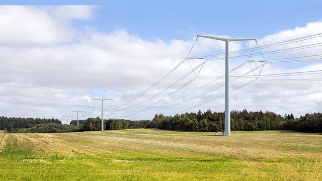 New electricity T-pylons and overhead lines running across a field with woods in the background