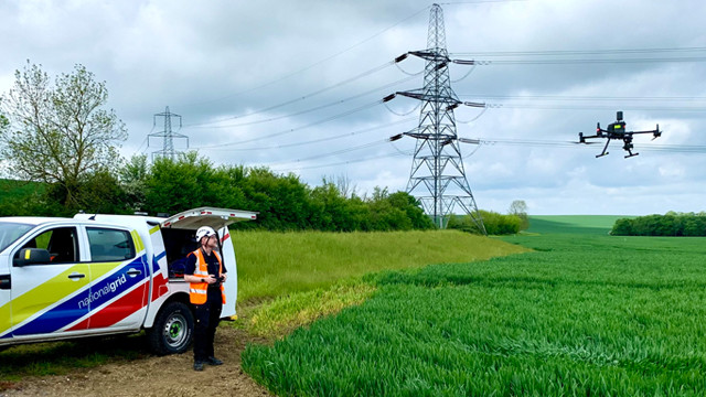 National Grid engineer wearing PPE piloting a drone near electricity transmission lines