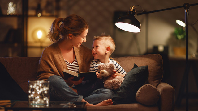 Mother and child on sofa reading by floor lamp