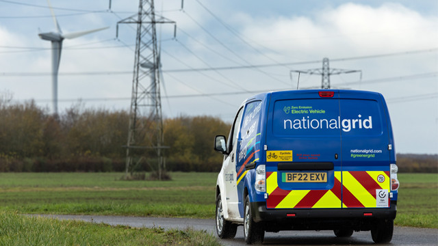National Grid EV van seen from behind in a field with electricity pylons and a wind turbine in the background