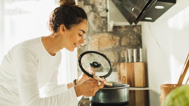 Woman stirring cooking in a saucepan in the kitchen