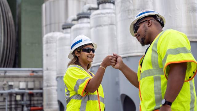 National Grid colleagues wearing PPE and bumping fists at Newtown Creek in NY