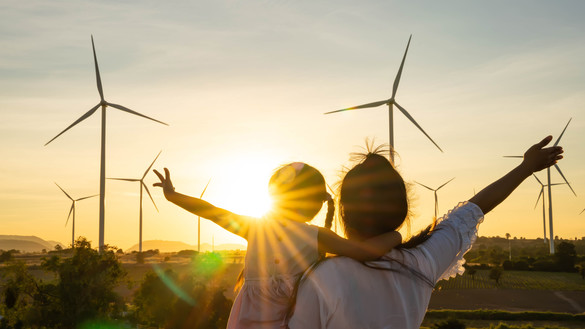 family in front of the sun and onshore wind farm