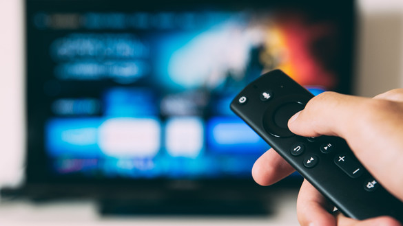 Hand holding a TV remote control pointed at TV screen - used for National Grid ESO story 'The 'lockdown effect' on TV viewing habits and the electricity grid'