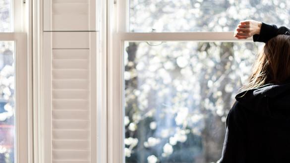 Woman looking through a window - social distancing - used for the National Grid story 'Caring for mental health during a crisis'