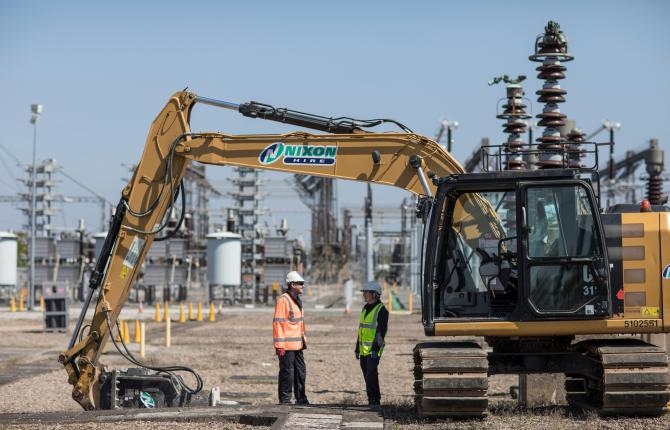 Two National Grid representatives talking in the foreground of a construction site 
