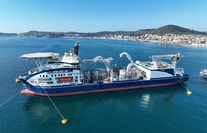 Cable laying vessel moored near land on a sunny day