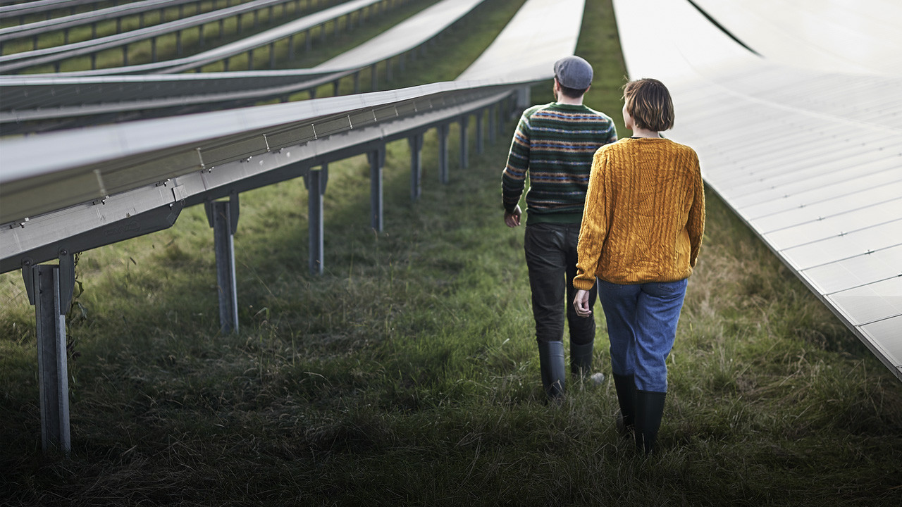 National Grid COP26 - man and woman walking between rows of solar panels in a solar farm