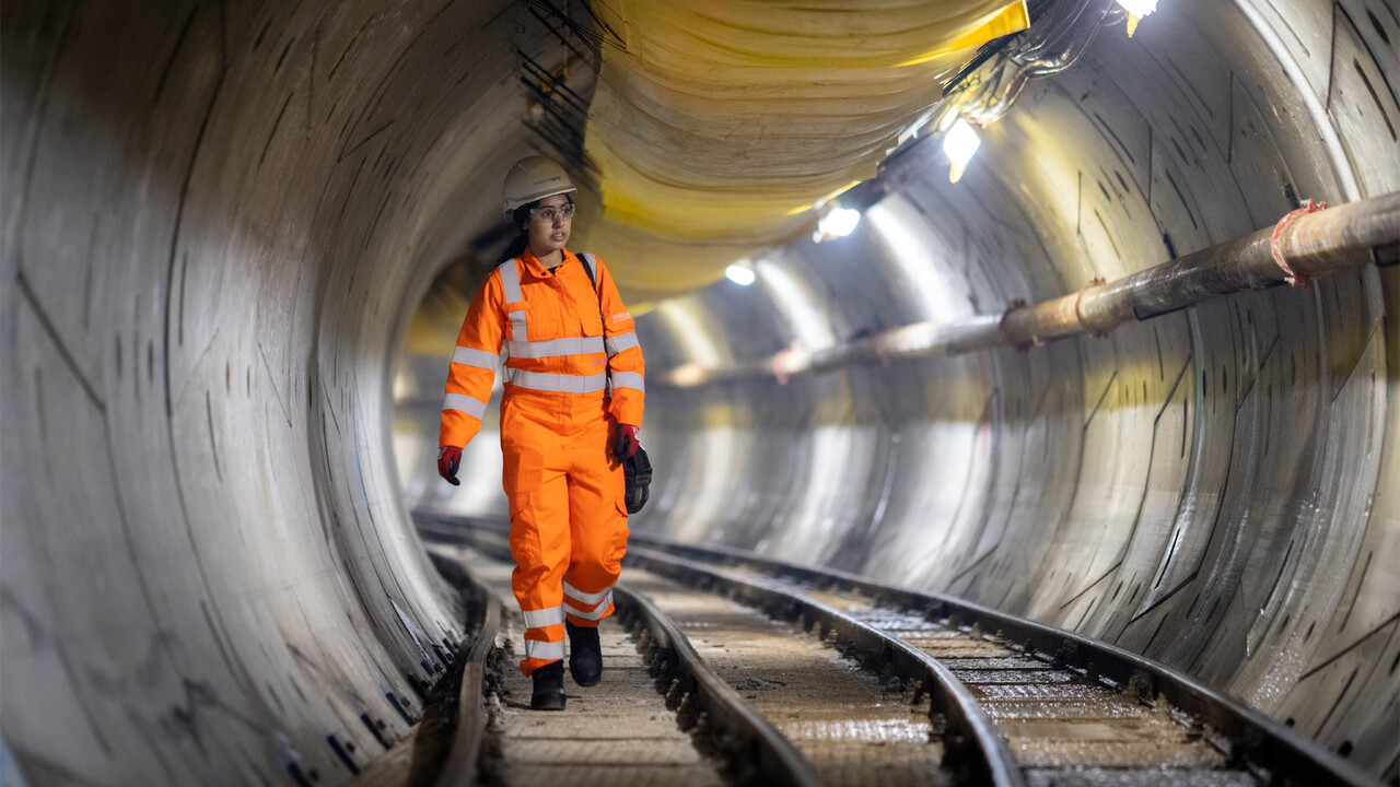 An engineer wearing hard hat and PPE walking inside London Power Tunnels