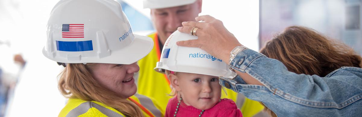 A group image of a family wearing National Grid hard hats - Communities 