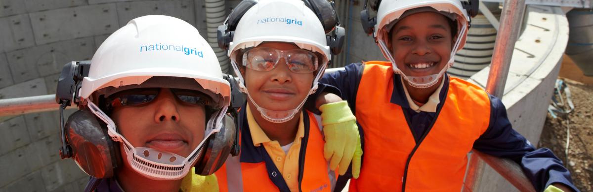 Three young National Grid representatives with a gas construction in the background - People