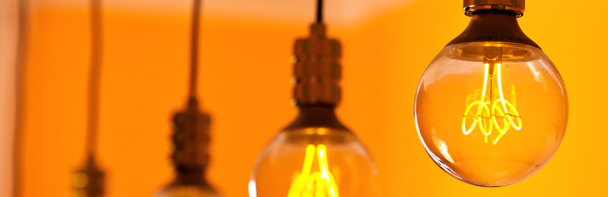 Row of lightbulbs hanging in a room with orange walls - used for the National Grid story 'Britain’s electricity explained: new monthly report shows how we use power'