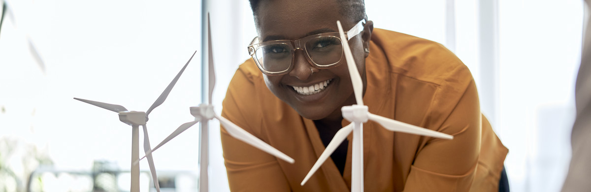smiling employee behind a model of a wind farm