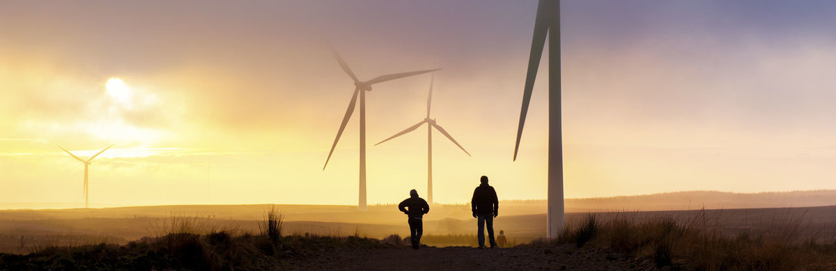 People walking across fields next to wind turbines - used for the National Grid story 'National Grid launches green bond to fund sustainability projects'
